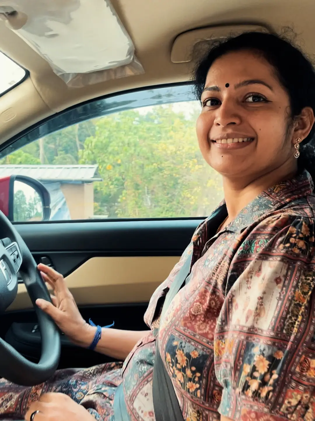 Anjana smiling behind the wheel